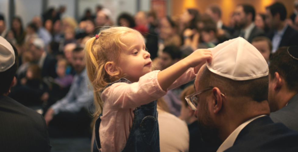 Young girl placing a kippah on her father's head